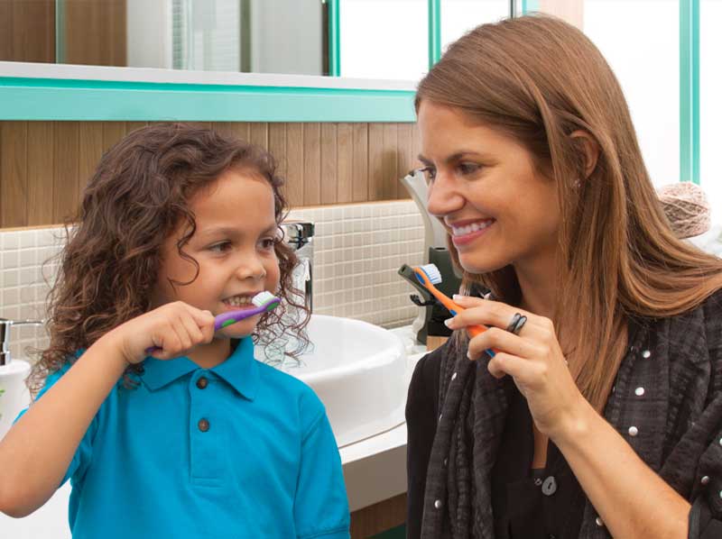 Woman and child brushing teeth